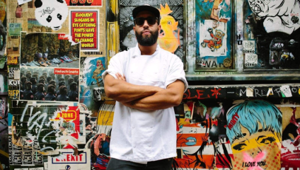 James Cochrane stands, owner and head chef at Islingston’s 12:51 restaurant, stands in his chefs apron,  a cap and sunglasses with his arms folded, in front of a colourfully-graffitied wall