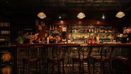 Wooden bat stools sit at the cool, dimly-lit bar of London's Night Jar bar in Shoreditch