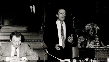 A black and white photograph of Akyaaba Addai-Sebo, founder of Black History Month in the UK, standing to speak at a conference