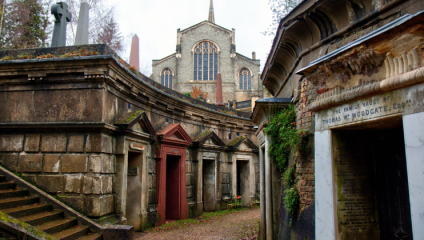 On a wintery day, among the tombs below ground at Highgate Cemetery; a church stands above ground in the distance