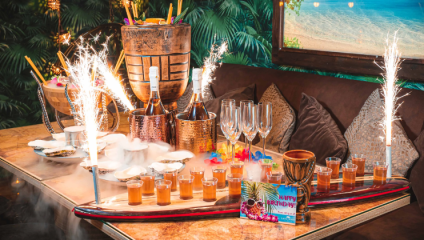 A table in the Hawaiian-themed Laki Kane restauant holds a tray of shots and a cooler of liquor with sparklers going off around it