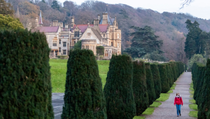 A woman walks through the tree-lined gardens of Tyntesfield House in North Somerset