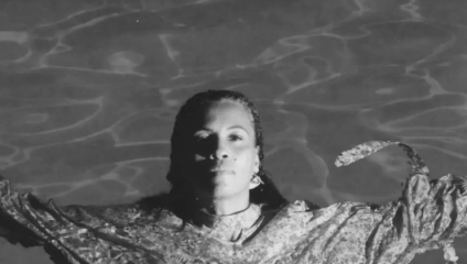 A black and white photograph of Swedish singer-songwriter Neneh Cherry floating in water as she looks into the camera from below