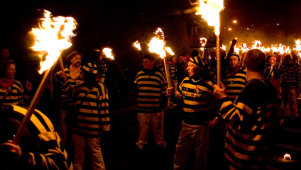 Dozens of men, all dressed as cartoon robbers (in black-and-white striped tops) carry torches through the streets of Lewes for the Nevill Juvenile Bonfire Night