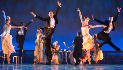 In a production by Northern Ballet, dancers in 1920s-style dress (men in top hats and tails, women in flapper dresses) leap gaily into the air with their sarms stretched upwards