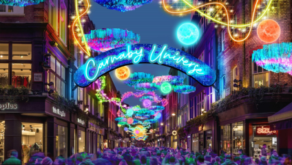 A funky, multi-coloured Christmas light display above Carnaby Street, which is packed out with shoppers. The title signs reads ‘Carnaby Universe’