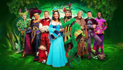 The cast of the pantomime Robin Hood at The London Palladium, in costume against a green forest pantomime set background