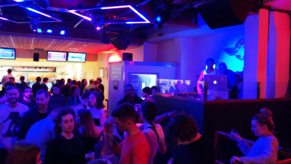 The interior of Rowans Tenpin Bowl in Finsbury Park; people dance as a DJ plays while others bowl in the background