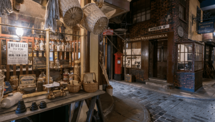 An exhibition inside Salford Museum and Art Gallery showing a street in Salford as it would have been in the Victorian era. We see the cobbled stones of the street beyond a seller’s kiosk