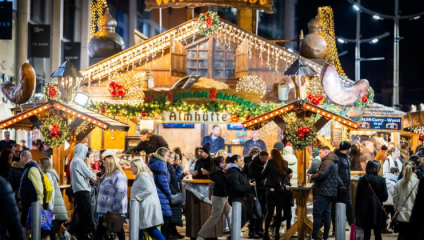 A Christmas market in Manchester bustling with people in the bright lights from different festive stalls