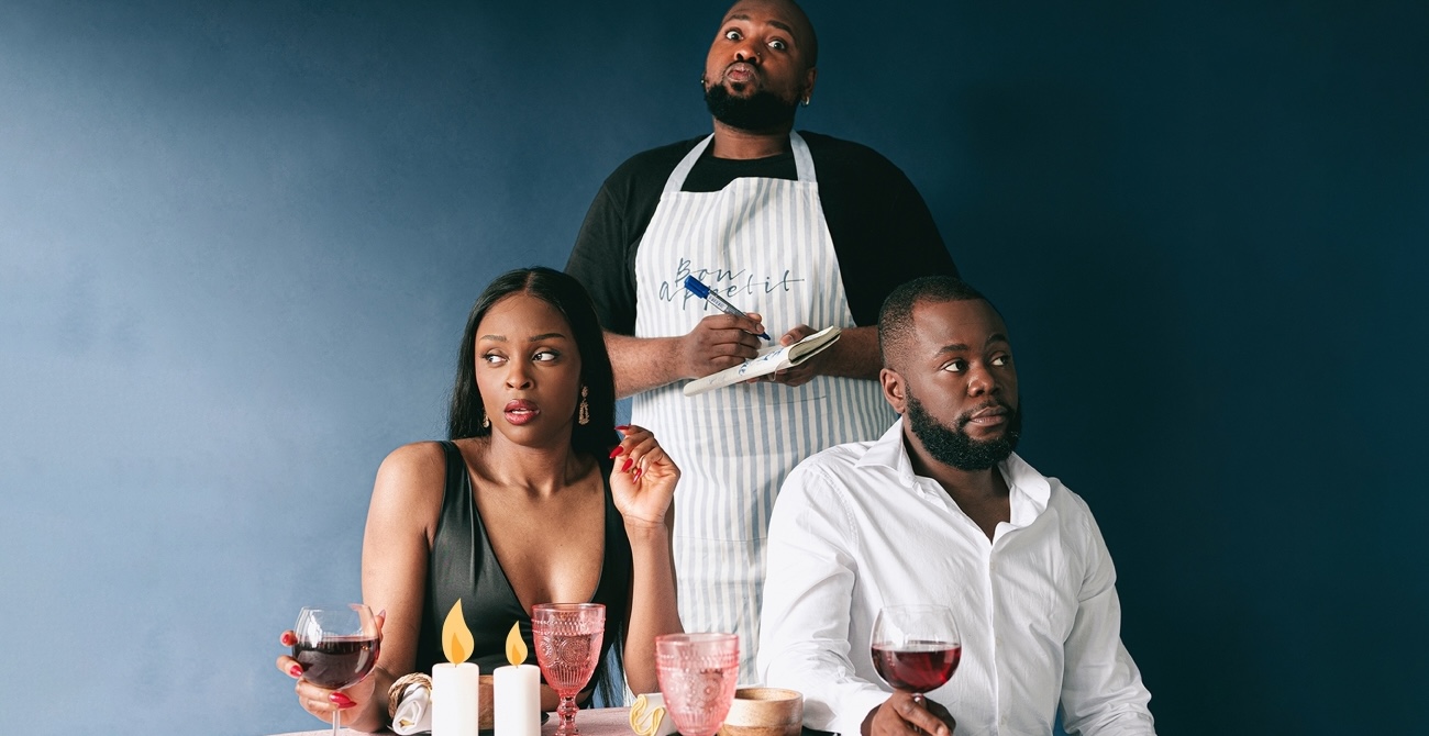 A woman and a man sit at a candlelit table with wine glasses, looking slightly surprised and concerned. A waiter holding a notepad and wearing an apron stands behind them, looking upward with a pondering expression. The background is a deep blue.