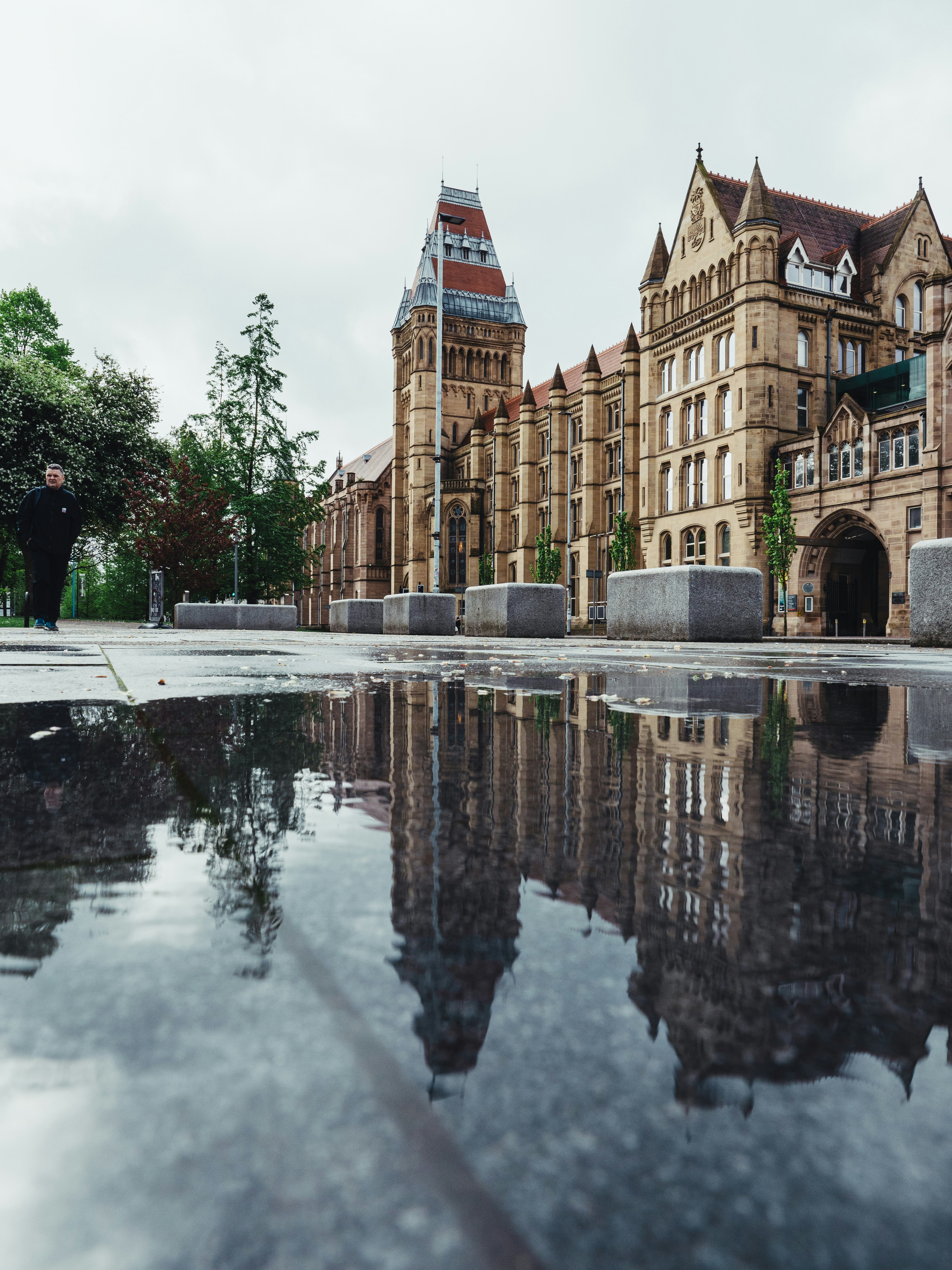 Outside the Victorian gothic Manchester Museum, large puddle of water in the foreground