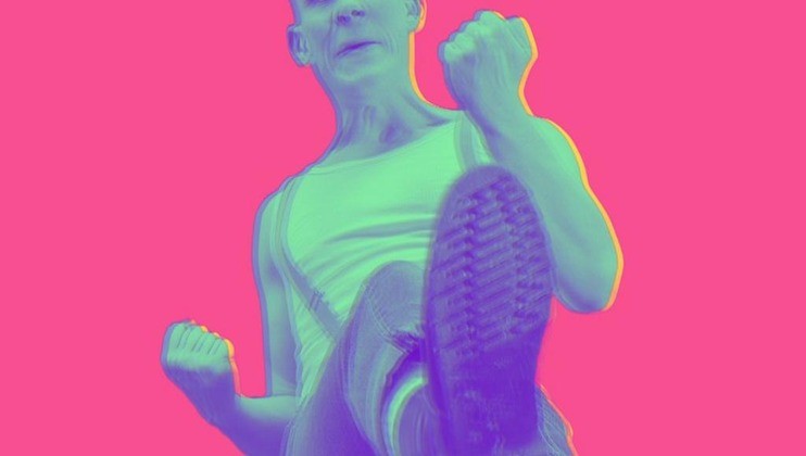 A person wearing a white tank top and suspenders is depicted in a colorful, high-contrast image with a bright pink background. They are lifting one leg, showing the sole of their shoe, and have their fists clenched in an energetic pose.