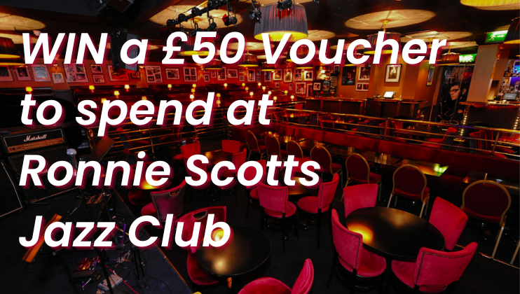 Image of an empty jazz club with red seating and a stage with musical equipment. The text reads, WIN a £50 Voucher to spend at Ronnie Scott's Jazz Club. The venue has a warm, inviting atmosphere with dim lighting.
