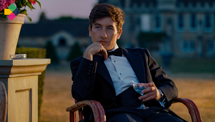 A man in a tuxedo sits relaxed in a chair holding a cocktail glass with clear liquid and an olive. He rests his chin on his hand, gazing into the distance. The background features an elegant building and a potted plant on a stone pedestal.