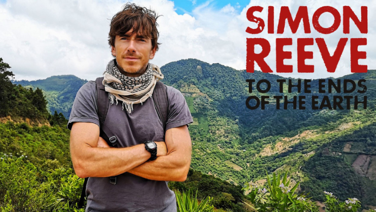 A person stands outdoors with arms crossed, wearing a scarf and a gray t-shirt. Behind them, lush green mountains stretch to the horizon under a partly cloudy sky. Text on the right reads SIMON REEVE TO THE ENDS OF THE EARTH.